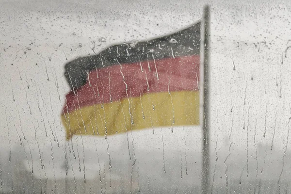 在雨中 德国国旗在玻璃窗后面模糊的背景下飘扬 这对德国来说是一个悲惨而戏剧性的日子 — 图库照片