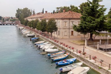 İtalya 'nın Veneto eyaletinde, Verona eyaletindeki Peschiera del Garda tatil köyünde göldeki körfezde küçük tekneler.
