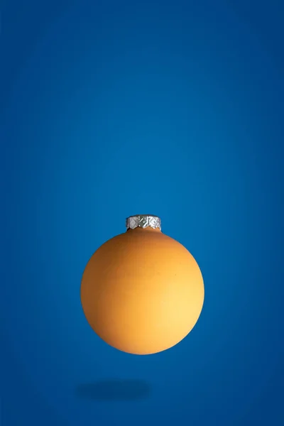 Flying gold Christmas yellow ball, levitation concept with space for text, blue background — Stock Photo, Image