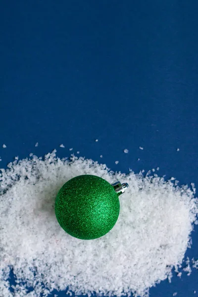 Verde brillante brillante bola de Navidad aislado en la nieve, plantilla con espacio para el texto — Foto de Stock