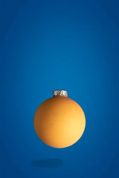 Létající zlato Vánoční žlutý míč, levitační koncept s prostorem pro text, modré pozadí — Stock fotografie