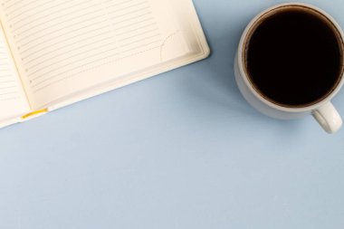 açık mavi renkli masa üzerinde defter ve fincan kahve, minimalist tasarım