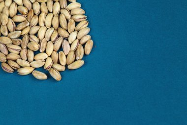 Fıstık tohumu dokusu mavi arkaplandaki üst görünüm, metin için alan, organik sağlıklı gıda kavramı