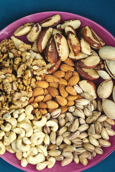 Badem, fıstık, ceviz, Brezilya cevizi, pekan cevizi, pekan tohumları mavi arka plan üst görünüm, yazı için alan, organik sağlıklı gıda kavramı
