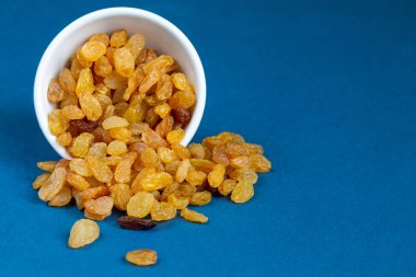 Mavi arka planda bir kasede kuru üzümler, mesaj için boş alan. Sağlıklı organik gıda konsepti