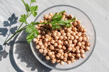 Gri bir masanın üstünde cam bir kasede nohut doğal güneş ışığı ve sert gölge. Sağlıklı beslenme konsepti