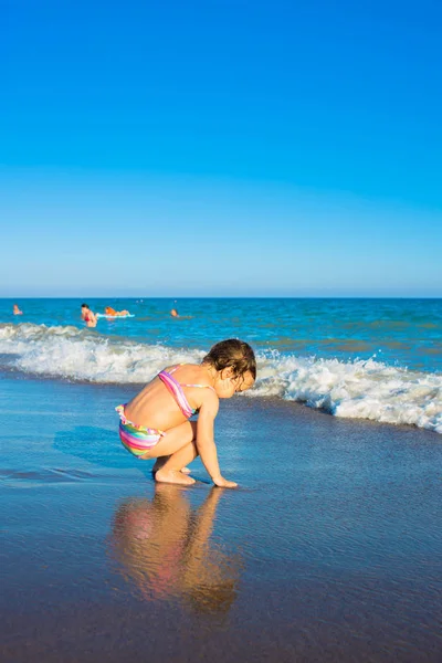 Kleines Mädchen spielt am Meeresstrand. — Stockfoto