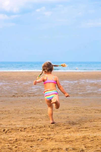 Malá holčička vede přes pláž. — Stock fotografie