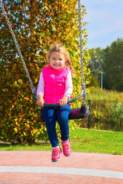 Meisje op een schommel swingende lachen. — Stockfoto