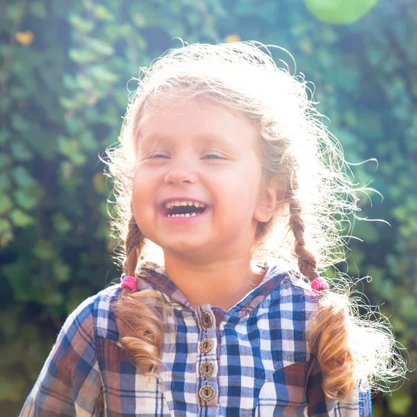 Porträtt av glad liten skrattande flicka med flätor. — Stockfoto