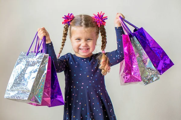 Улыбающаяся маленькая девочка с сумками для покупок. Чёрная пятница — стоковое фото
