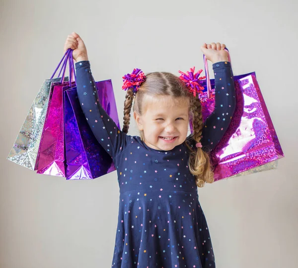 Petite fille souriante avec des sacs à provisions avec des cadeaux . — Photo