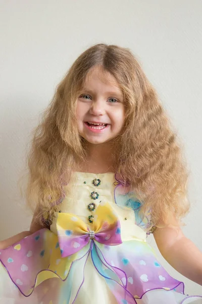 Beautiful smiling little girl with long blond curly hair. — Stock Photo, Image