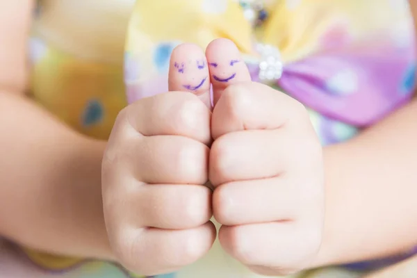 Uma criança pequena mostrando os polegares com rostos sorridentes . — Fotografia de Stock