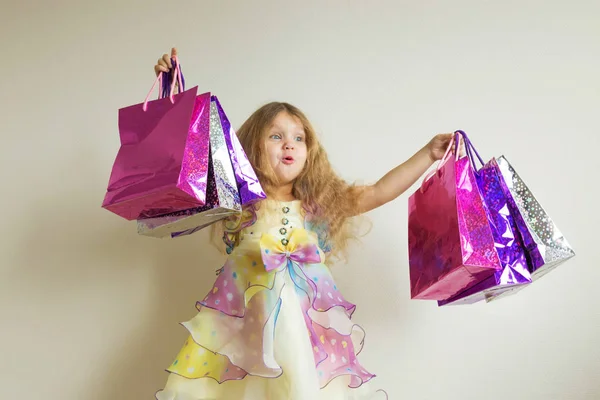 Sorpresa felice bambina tiene un sacco di borse della spesa di carta — Foto Stock