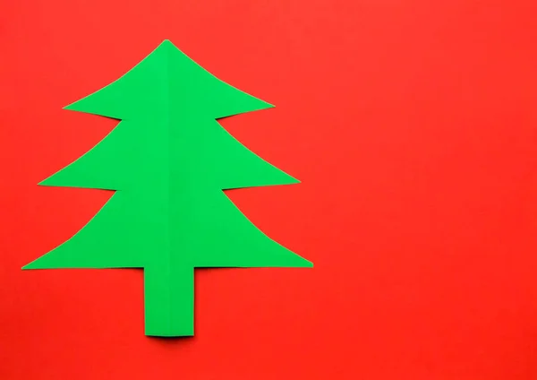 Christmas tree carved from colored green paper on a red backgrou — Stock Photo, Image