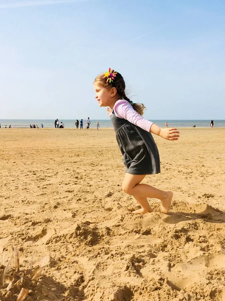 Podél pláže vede naboso malé malé radostné holčičky — Stock fotografie
