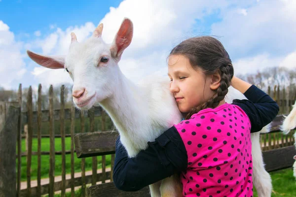 Little girl embracing a kid goat on a farm. — Stock Photo, Image