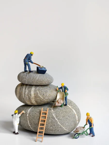 Pebbles stack and figurines of construction — Stock Photo, Image