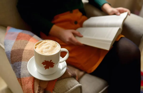 Cup of cappuccino and girl reading a book — Stock Photo, Image