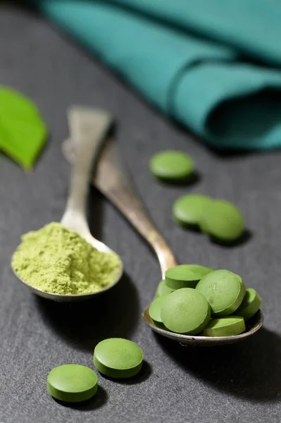 Chlorella und Gerstenpulver auf Löffeln auf Ardesia — Stockfoto