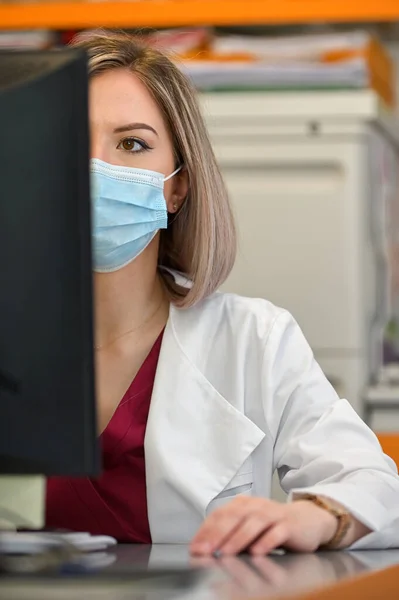 A Doctor In A Mask Works On A Computer