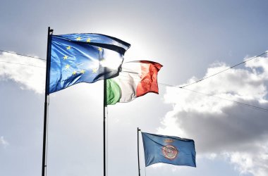 Avrupa bayrağı, italyan bayrağı ve Nemi 'nin bayrağı açık bir gökyüzünde birlikte dalgalanıyor. Avrupa Birliği ile İtalya arasındaki ilişki hakkında. Nemi, İtalyan köyü, Lazio, İtalya.