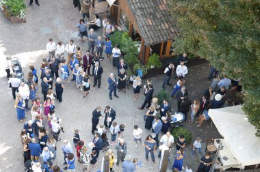 Büyük bir grup iyi giyimli insan yeşil bir yerleşim bölgesinde köy caddesinde sosyalleşiyorlar. Üst görünüm.