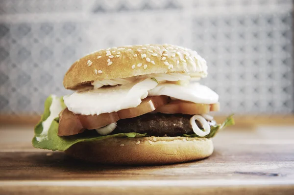 Üzerinde taze mozzarella peyniri, domates, fesleğen yaprağı ve ahşap kesim tahtasında kızartılmış brioche ekmeği ve marul dilimleri olan Caprese tarzı hamburger. Ev yapımı ve sağlıklı sandviç. İtalyan stili.