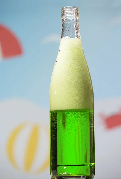 Open bottle with tarragon carbonated drink and foam