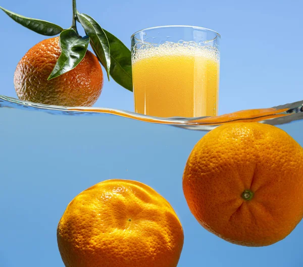 Tangerine with leaves, a glass of carbonated drink and a pair of tangerines under water