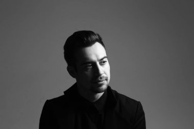 Ciddi genç yakışıklı bir adam bir takım, dramatik siyah beyaz portre aydınlatma, düz studio arka planı.