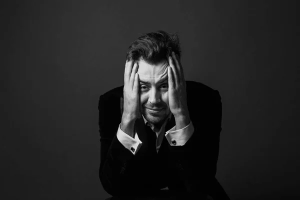 Kafasına kamera düz studio arka plan bakarak bir takım, üzgün, yakışıklı bir genç adam portresi siyah ve beyaz eller.