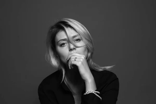 Kamera için arayan genç bir kadın portresi siyah ve beyaz bir stüdyo düz arka plan onun ağzına ellerimi