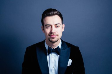 Kameraya düz studio arka plan karşı ciddi görünümlü genç yakışıklı bir adam bir takım, portresi.