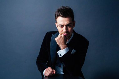 Yakışıklı adam giymiş siyah, dramatik aydınlatma, ciddi bir genç portresi kameraya bakarak yüz, el