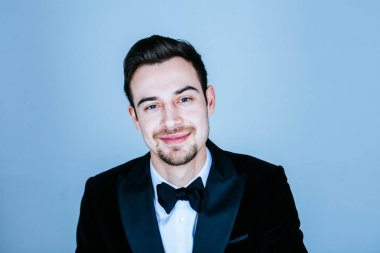 Gülümseyen ve kamera düz studio arka plan bakmak genç yakışıklı bir adam bir takım, portresi.