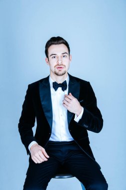 Oturma ve kamera düz studio arka plan bakarak bir takım, yakışıklı bir genç adam portresi.