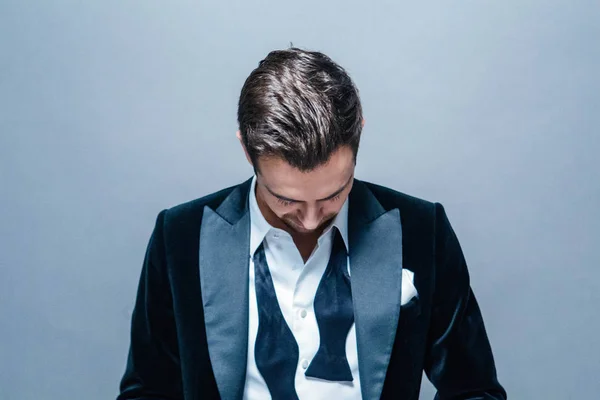 Aşağı, düz studio arka planı arıyorum genç yakışıklı bir adam bir takım elbise, kravat ve gömlek düğmeleri yapılmadıkları içinde portresi