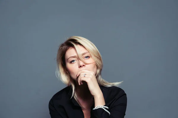 Yüz, bir stüdyo düz arka plan yakınındaki elini tutarak kameraya bakarak üzgün genç bir kadın portresi kapatın