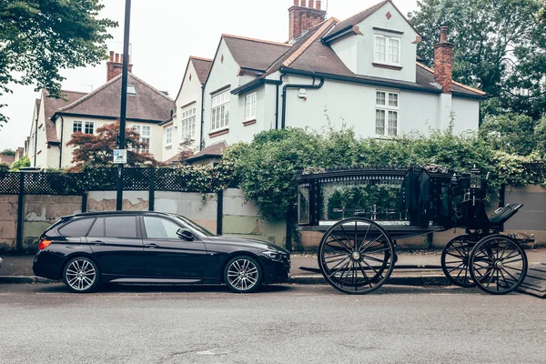 BMW Touring and a hearse parked on a side of a street in London — Stock Photo, Image