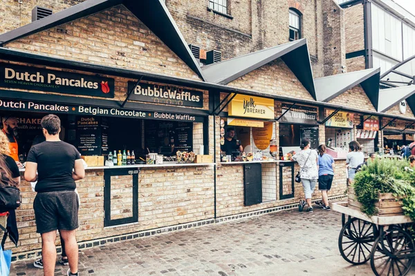 İnsanlar Londra 'daki Stables Market' ten yiyecek alıyor.