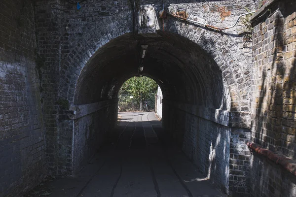 Dark pedestrian tunnel under the railway near Barnes railway station in the south-west London; a light at the end of a tunnel concept