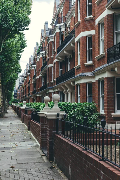 The row of large late Victorian blocks of mansion flats. Typical British houses are the form of medium-density housing that originated in Europe, whereby a row of attached dwellings share sidewalls