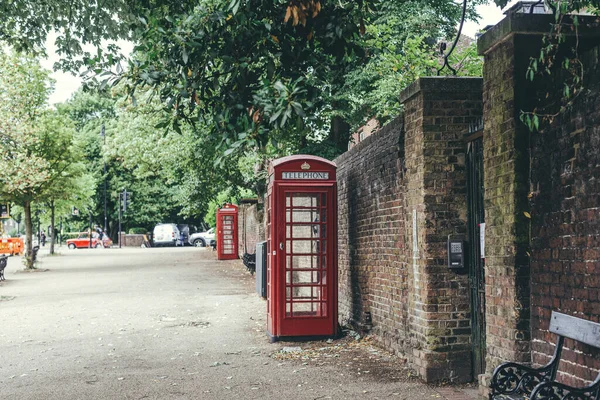 Traditional red telephone box on a street in London. The red phone box is often seen as a British cultural icon throughout the world. It is one of Britain\'s top 10 design icons
