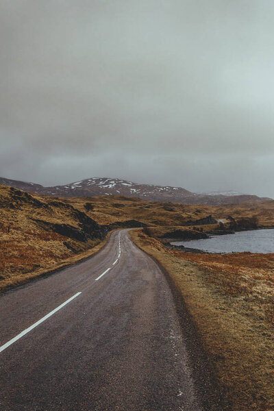 Scenic view of a road along the lake in a valley in Scottish highlands