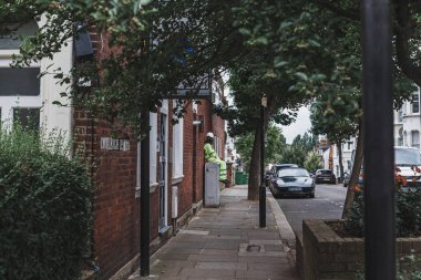 Londra / İngiltere-30 / 07 / 18: kaldırımda oturan, dinlenen, Londra 'da bir caddenin duvarına yaslanan inşaat işçisi