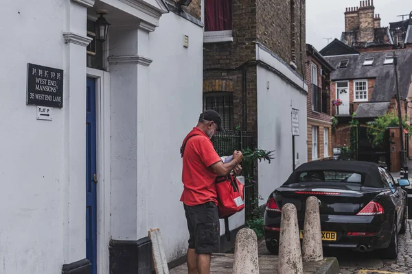 Londra / UK-30 / 7 / 18: Kraliyet Postacısı posta dağıtıyor. Posta çantası, postacı tarafından belirlenmiş bir rotada posta dağıtımına yardımcı olmak için kullanılan bir posta çantasıdır.