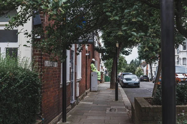 Londra / İngiltere-30 / 07 / 18: kaldırımda oturan, dinlenen, Londra 'da bir caddenin duvarına yaslanan inşaat işçisi