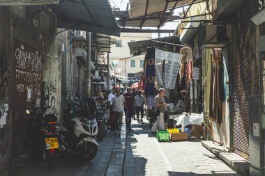 Tel Aviv / İsrail-10 / 10 / 18: Sıcak, güneşli bir yaz gününde, Eski Jaffa şehrindeki Jaffa Bit Pazarı 'nın dar bir caddesinde yürüyen insanlar